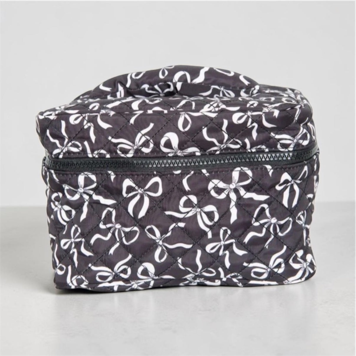 Black and white coquette bows quilted cosmetic bag with bow pattern and zip closure.