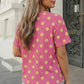 Back view of a woman wearing a pink polka dot patch pocket twisted ribbed top.