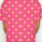 Back view of a bright pink twisted-ribbed top with yellow polka dots.