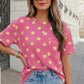 Model wearing pink twisted ribbed top with yellow polka dots and a patch pocket.