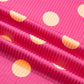 Close-up of pink twisted ribbed knit fabric with peach polka dots.