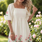 Beige floral print puff sleeve babydoll dress worn by a model in a garden