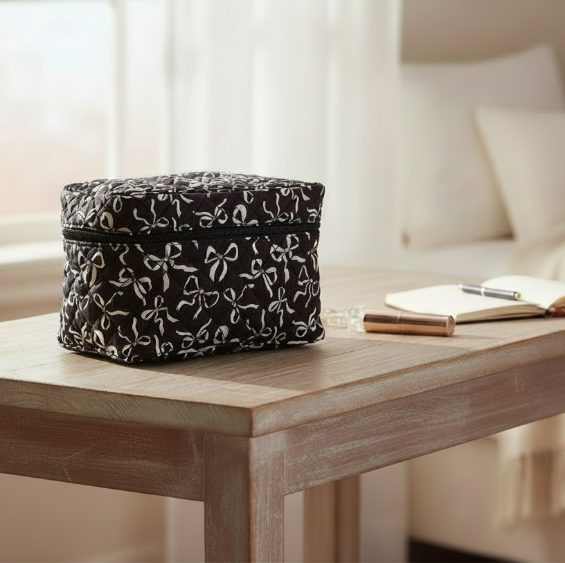 Black and white Coquette Bows quilted cosmetic bag on a wooden table.
